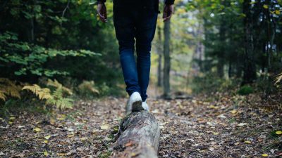 Man walking on a log through a forest