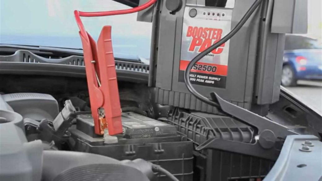 A Booster PAC jump starter connected to a car battery to jump start the car