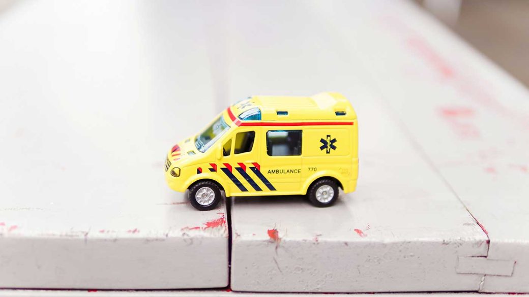 Yellow toy ambulance on a painted wood table