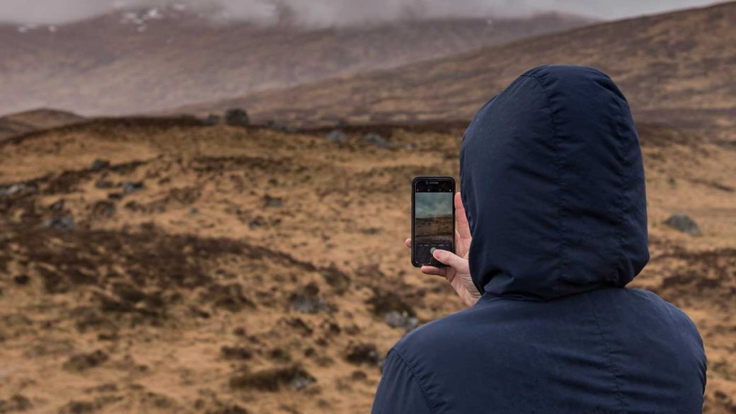 Travel influencer taking a photo of the Scottish Highlands for Instagram