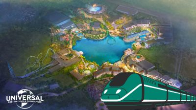 Aerial illustration of a Universal UK theme park layout, featuring a stylized green train graphic in the foreground—highlighting direct trains from Europe—and the Universal Destinations & Experiences logo in the corner.