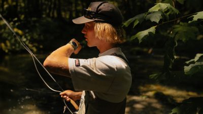 A fly-fisherman using the voice note feature on the Coros Nomad GPS fishing adventure watch.