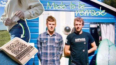 Mart & Rob Drake-Knight, founders of the sustainable clothing brand Rapanui, stand in front of a blue and white hut. Inset images show a ‘remill’ QR code tag, a person in Rapanui jeans, and text reads “Made to be remade,” showing how this Isle of Wight brand made sustainable fashion mainstream.